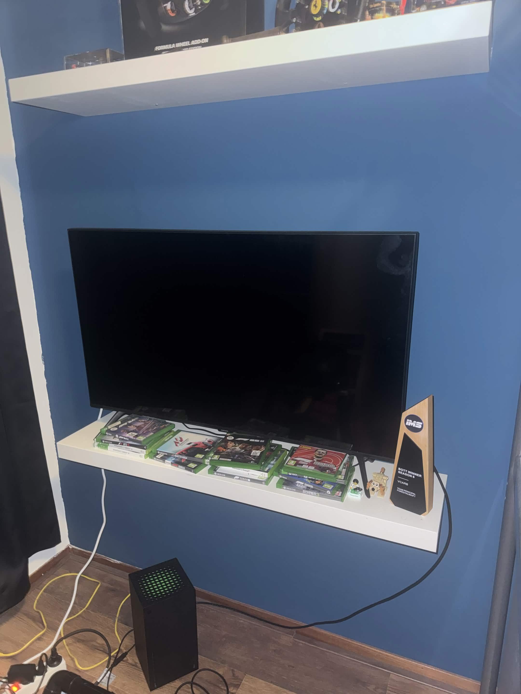 Forestal's Season 6 VCARB BOTT trophy on a white shelf beside his screen.